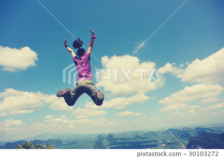 cheering oung woman jumping on mountain peak 30103272