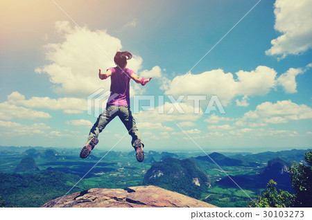 cheering oung woman jumping on mountain peak 30103273