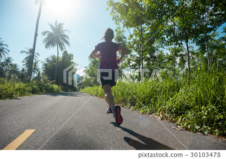 woman runner running at tropical forest trail 30103478