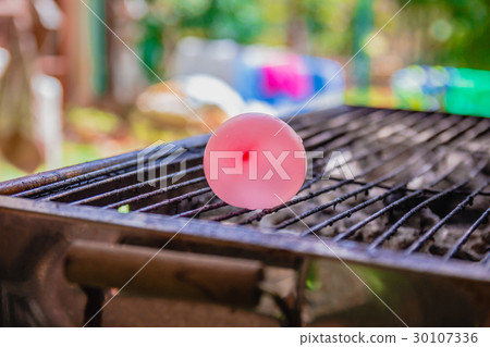 Balloon filled with water placed on a hot grill 30107336