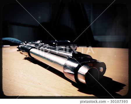 Silver 9mm pistol lying on a wooden table Silver 9mm pistol lying on a wooden table 30107393