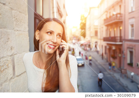 Young woman calling phone standing on balcony 30109079