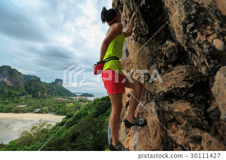 woman rock climber climbing at seaside cliff woman rock climber climbing at seaside cliff 30111427
