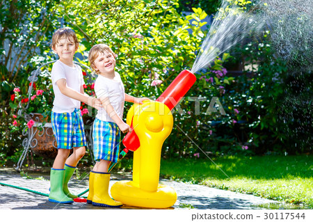 Two little kids boys playing with a garden hose Two little kids boys playing with a garden hose 30117544