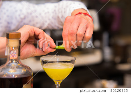 Barman putting lemon peel to prepare coctail Barman putting lemon peel to prepare coctail 30120535
