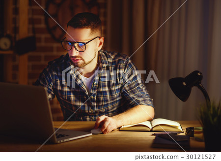 man working on computer at home at night in dark 30121527