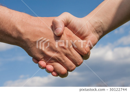 Man's handshake against a blue cloudy sky Man's handshake against a blue cloudy sky 30122744