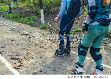 Two girls ride on rollers on a very bad road Two girls ride on rollers on a very bad road 30126617