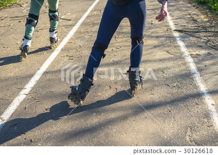 Two girls ride on rollers on a very bad road Two girls ride on rollers on a very bad road 30126618