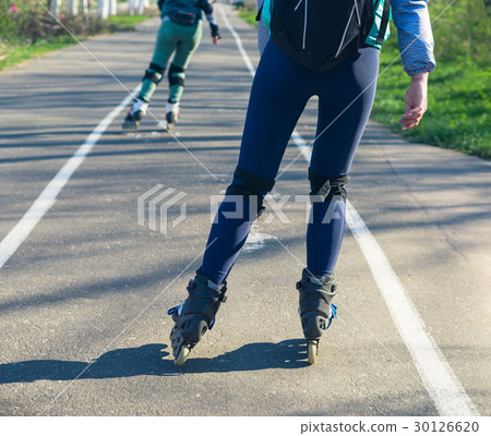 Two girls on roller skates ride along the road 30126620