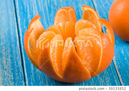 one peeled tangerine on a blue wooden background one peeled tangerine on a blue wooden background 30133852