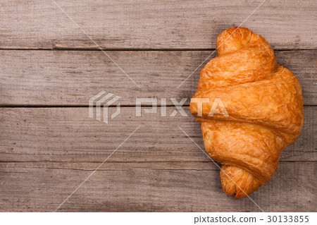 one croissant sprinkled on old wooden background one croissant sprinkled on old wooden background 30133855