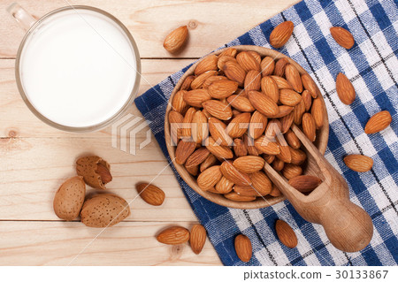Almond milk in a glass and almonds in a bowl on Almond milk in a glass and almonds in a bowl on 30133867