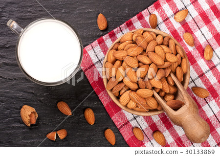 Almond milk in a glass and almonds in wooden bowl Almond milk in a glass and almonds in wooden bowl 30133869