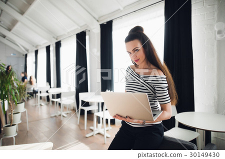 Smiling adult woman standing in a cafe with a 30149430