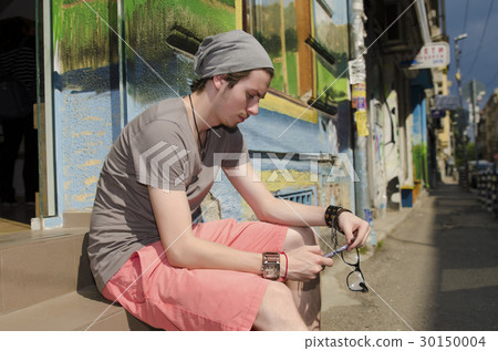 Teenager looking at his mobile phone Teenager looking at his mobile phone 30150004