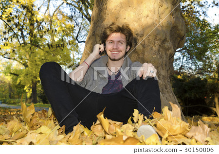 Teenager sitting under the tree among leaves Teenager sitting under the tree among leaves 30150006