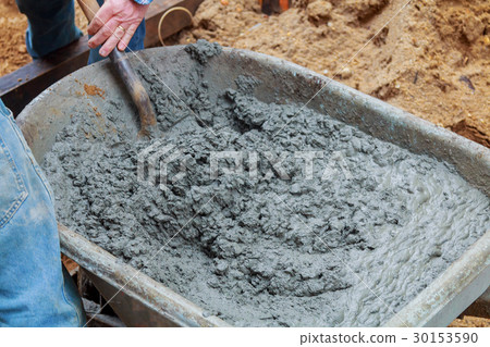 Worker shovels a wet mix of concrete 30153590