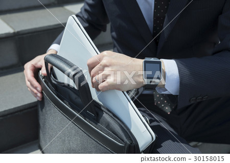 A businessman who takes out a laptop computer from a business bag 30158015