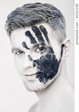 Young man with black hand print on white face Young man with black hand print on white face 30161288