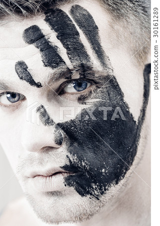 Young man with black hand print on white face Young man with black hand print on white face 30161289