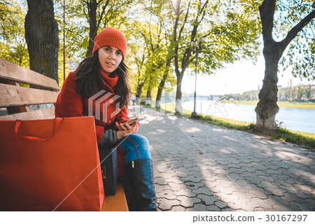 Young stylish woman sits on bench after shopping Young stylish woman sits on bench after shopping 30167297