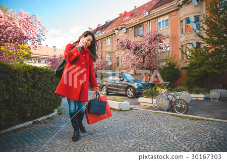 woman stands with paperbags and talking on the 30167303