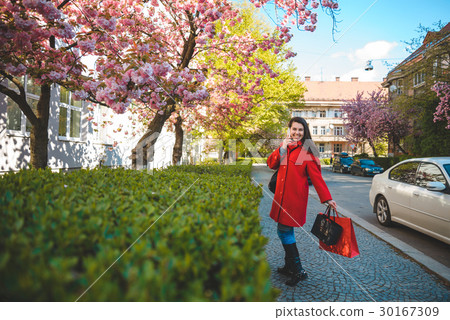 woman stands with paperbags and talking on the 30167309