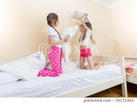 Two girls fighting with pillows at bedroom 30172403