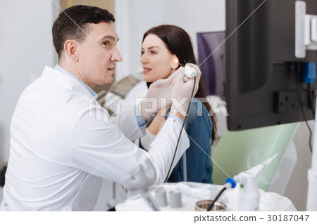 Attentive otolaryngologist examining hearing of 30187047