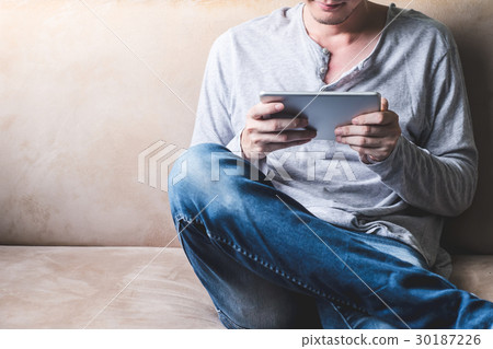Casual young man using tablet on sofa at home. Casual young man using tablet on sofa at home. 30187226