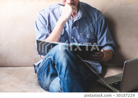 Casual young man reading documents on sofa Casual young man reading documents on sofa 30187229