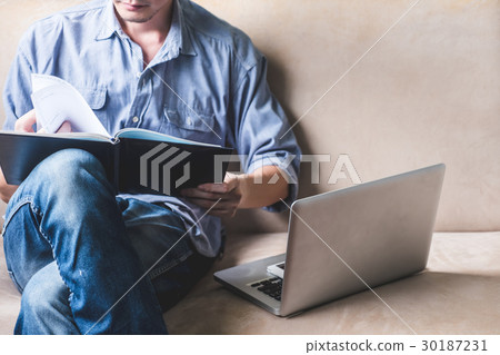 Casual young man reading documents on sofa Casual young man reading documents on sofa 30187231