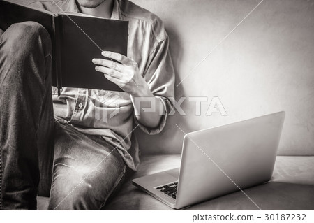 Casual young man reading documents on sofa Casual young man reading documents on sofa 30187232