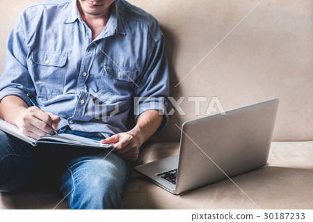 Casual young man writing some data in notebook 30187233