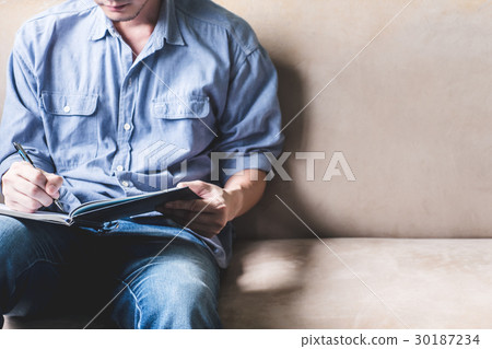 Casual young man writing some data in notebook Casual young man writing some data in notebook 30187234