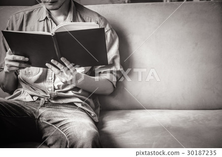Casual young man reading documents on sofa Casual young man reading documents on sofa 30187235