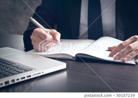 Businessman writing some data in notebook Businessman writing some data in notebook 30187239