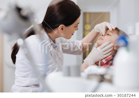 Serious otolaryngologist examining nose problems Serious otolaryngologist examining nose problems 30187244