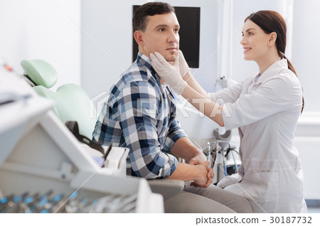 Delighted female otolaryngologist sitting opposite 30187732