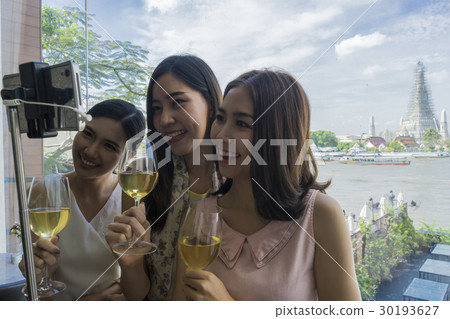 Ladies are taking selfie with temple background in a bangkok's restaurant Ladies are taking selfie with temple background in a bangkok's restaurant 30193627
