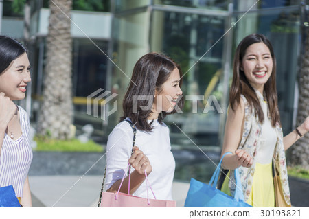 A group of women are walking in front of the building. 30193821