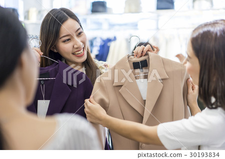 a woman is showing coat for her friends to choose. 30193834