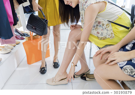 Pretty lady is trying on the brown shoes in the store. 30193879