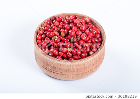 圖庫照片: pink pepper in a wooden bowl isolated on white