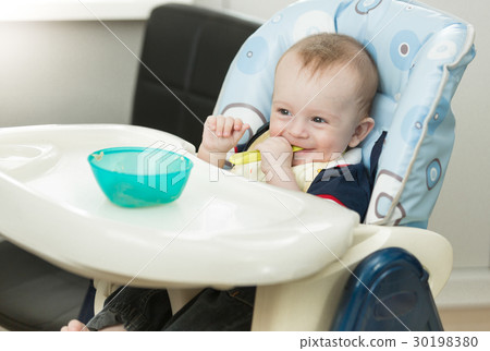 Baby playing with food and dish while eating 30198380
