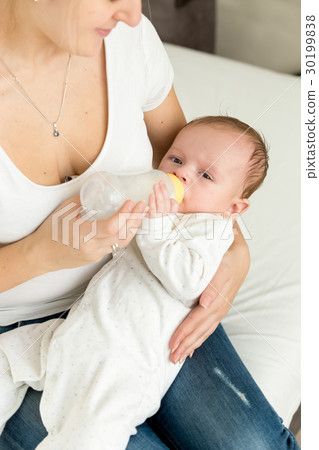 Young mother feeding her baby boy in bed Young mother feeding her baby boy in bed 30199838