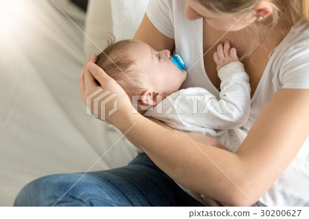 Toned image of baby boy sleeping on mothers hands Toned image of baby boy sleeping on mothers hands 30200627