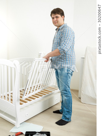 Young man assembling furniture in baby's room 30200647