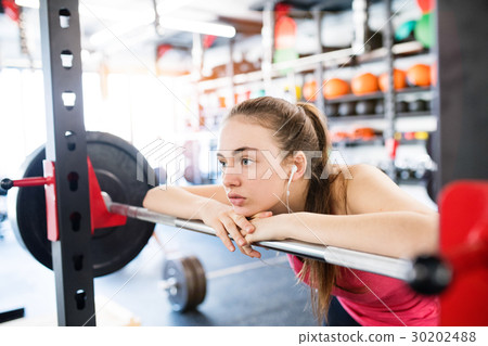 Young woman in gym, earphones in her ears 30202488